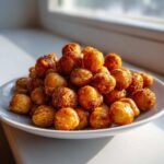A mound of golden brown, crispy Air Fryer Ranch Chickpeas piled high on a small white plate.
