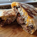 Cross-section view of a grilled BBQ Brisket Burritos stuffed with shredded meat, rice, cheese, and black beans.