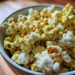 Close-up of a bowl filled with fluffy popcorn heavily coated in green and yellow Dill Pickle Seasoned Popcorn powder.