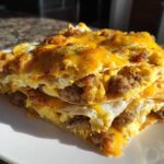 A rich stack of Breakfast Nachos with Sausage and Scrambled Eggs layered with tortillas and melted cheddar cheese.