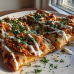 Close-up of two slices of Buffalo Chicken Flatbread Pizza topped with shredded chicken, cheese, ranch drizzle, and parsley.