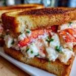 A close-up of a decadent Butter-Poached Lobster Tail Sandwich featuring creamy lobster salad and toasted brioche.