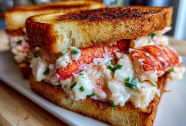 A close-up of a decadent Butter-Poached Lobster Tail Sandwich featuring creamy lobster salad and toasted brioche.