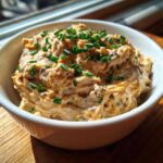 A close-up of creamy Caramelized Onion Neiman Marcus Dip, topped generously with fresh green chives.