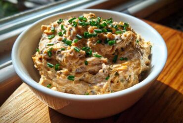 A close-up of creamy Caramelized Onion Neiman Marcus Dip, topped generously with fresh green chives.