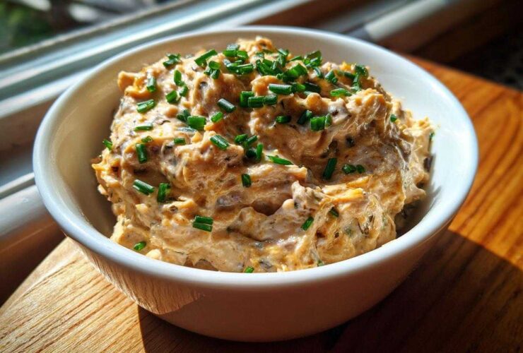 A close-up of creamy Caramelized Onion Neiman Marcus Dip, topped generously with fresh green chives.