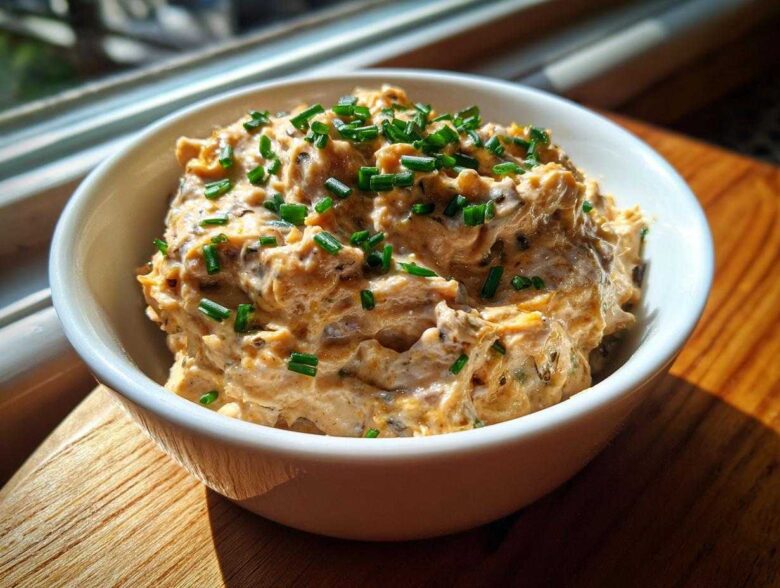 A close-up of creamy Caramelized Onion Neiman Marcus Dip, topped generously with fresh green chives.