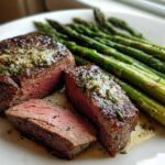 A perfectly cooked Cast Iron Filet Mignon, sliced to show medium-rare center, served alongside bright green asparagus spears.