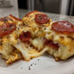 Close-up of cheesy Pepperoni Pizza Roll Ups, one is broken open showing a dramatic cheese pull.