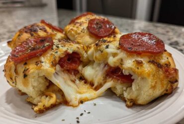 Close-up of cheesy Pepperoni Pizza Roll Ups, one is broken open showing a dramatic cheese pull.
