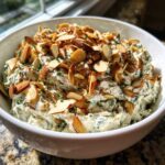 A creamy bowl of Chive and Almond Million Dollar Dip topped generously with toasted sliced almonds.
