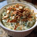 Creamy Chive and Almond Million Dollar Dip topped with toasted sliced almonds in a white serving bowl.