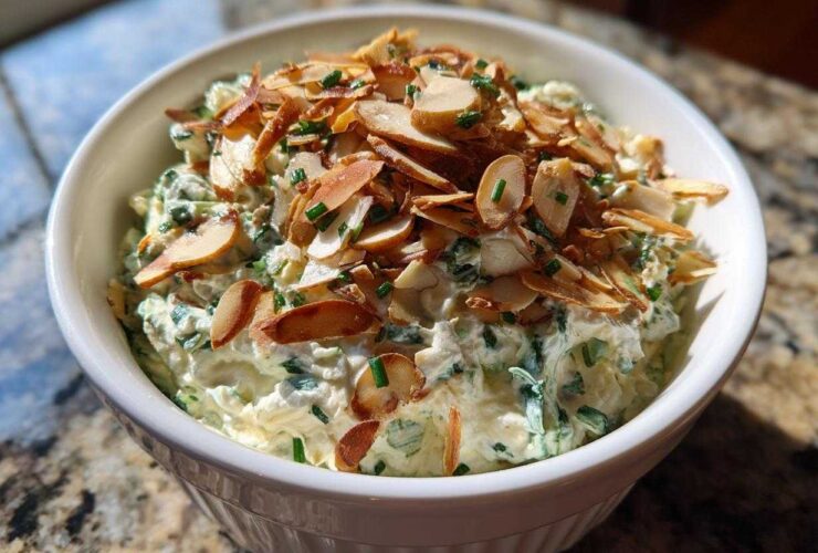 Creamy Chive and Almond Million Dollar Dip topped with toasted sliced almonds in a white serving bowl.