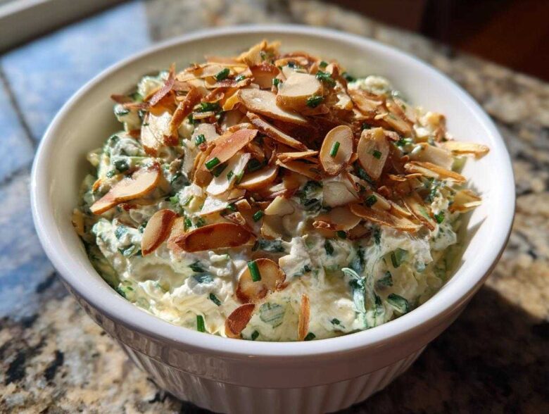 Creamy Chive and Almond Million Dollar Dip topped with toasted sliced almonds in a white serving bowl.