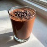 A glass of thick, rich Dark Chocolate Mint Breakfast Smoothie topped with chocolate shavings.