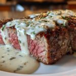A perfectly cooked medium-rare Filet Mignon with Gorgonzola Cream Sauce generously poured over the top.