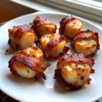 Six perfectly cooked Garlic Herb Bacon Wrapped Scallops arranged on a white plate.