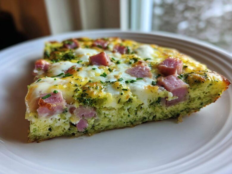 A close-up slice of Green Eggs and Ham Breakfast Pizza featuring green eggs, melted cheese, and diced ham.