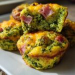 Close-up of baked Green Eggs and Ham Savory Muffins, showing green broccoli-flecked interior and pieces of pink ham.