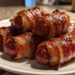 Close-up of several glazed Honey Mustard Bacon Wrapped Smokies piled on a white plate.
