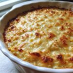 Close-up of baked Hot Corn and Crab Dip bubbling in a white dish with a golden, browned cheese crust.