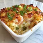 Close-up of Hot Shrimp Jalapeno Popper Dip with a golden crust and visible shrimp, garnished with green onions.