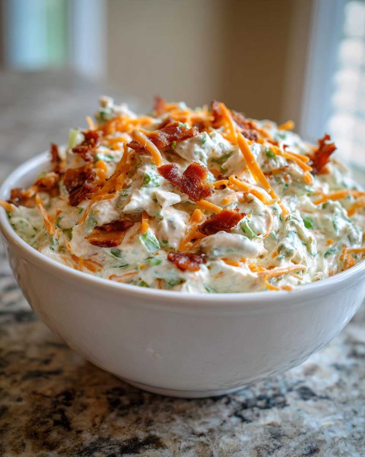 Close-up of Jalapeno Cheddar Million Dollar Dip topped with bacon and shredded cheddar.