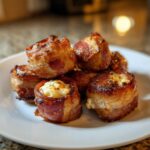 A pile of crispy, bacon-wrapped Kielbasa and Cream Cheese Pig Shots served on a white plate.