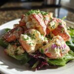 Generous serving of Lobster Tail Salad with Lemon Mayo Dressing piled high on mixed greens on a white plate.