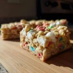 A close-up shot of a square of Lucky Charms White Chocolate Blondies, featuring colorful cereal pieces and marshmallows.