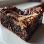 Close-up of a rich, fudgy Nutella Swirl Brownie Heart on a white plate, showing the marbled top.