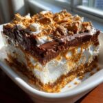A rich, layered slice of Dessert 7-Layer Dip featuring chocolate, peanut butter, cream, and a crumbly crust.