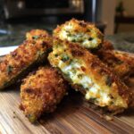 Close-up of crispy, golden-brown Pickle Stuffed Jalapeno Poppers, one cut open showing the creamy filling.