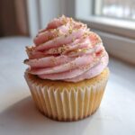 A single, beautifully frosted Pink Champagne Cupcakes with Gold Sprinkles, featuring pink frosting and edible gold flakes.