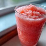 Close-up of a vibrant, icy Pink Lemonade Fruit Slushie filling a clear glass.