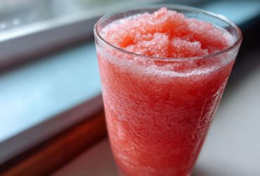 Close-up of a vibrant, icy Pink Lemonade Fruit Slushie filling a clear glass.