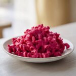 A close-up of bright Pink Macaroni and Cheese made with fusilli pasta coated in a vivid magenta sauce.