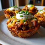 Close-up of a Pulled Pork Loaded Sweet Potato Bite topped with melted cheese, sour cream, and chives.