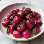 Close-up of vibrant purple Roasted Beet Gnocchi with Sage Butter in a white bowl.