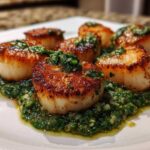 Close-up of perfectly seared scallops resting on a bed of vibrant spinach pesto.