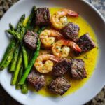 Close-up of Sheet Pan Steak and Garlic Butter Shrimp served with asparagus in a rich garlic butter sauce.