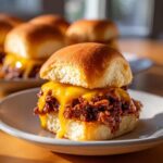 Close-up of a delicious Sloppy Joe Slider with melted cheddar cheese oozing over the saucy meat filling on a soft roll.