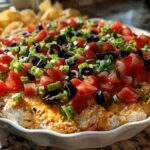 Close-up of a fully assembled Southern 7-Layer Dip with Pimento Cheese Base, topped with diced tomatoes, black olives, and green onions.