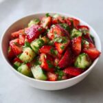 Close-up of vibrant Strawberry Cucumber Salsa with Lime, featuring chopped strawberries and cucumbers mixed with herbs.
