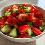 Close-up of vibrant Strawberry Cucumber Salsa with Lime, featuring chopped strawberries and cucumbers in a white bowl.