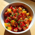 Close-up of vibrant Strawberry Peach Habanero Salsa, featuring diced red strawberries and yellow peaches, topped with fresh herbs.