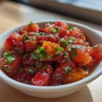 Close-up of vibrant Strawberry Peach Habanero Salsa with chopped fruit and herbs in a white bowl.