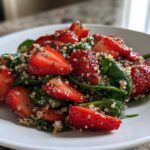 Close-up of a vibrant Strawberry Quinoa Spinach Salad featuring halved strawberries, green spinach, and quinoa tossed with poppyseeds.