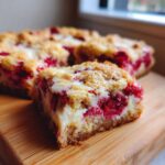 A close-up, mouthwatering square of White Chocolate Raspberry Blondies showing the gooey white chocolate and bright red raspberries.