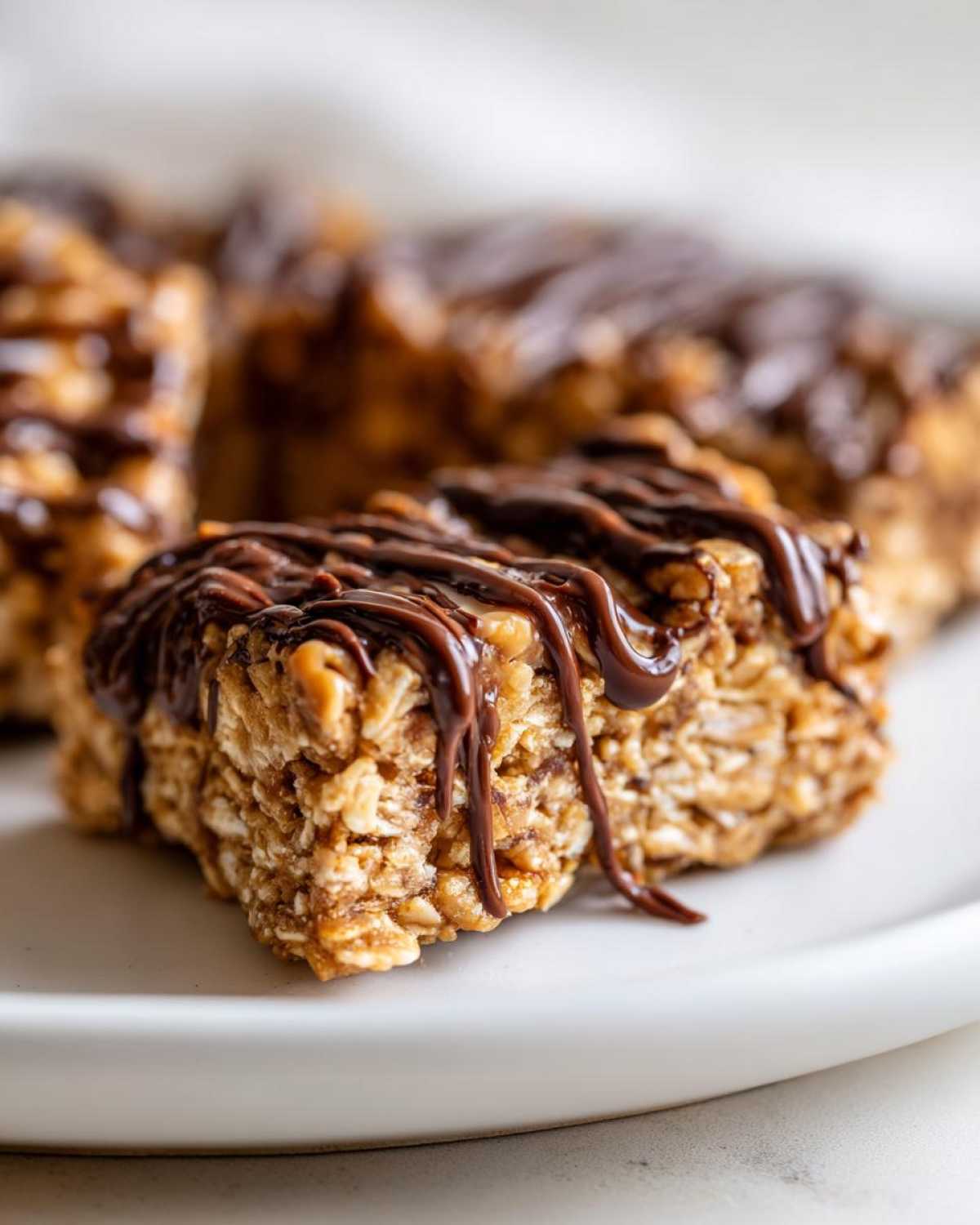 A close-up of a homemade protein bar made with oats, drizzled generously with melted dark chocolate.